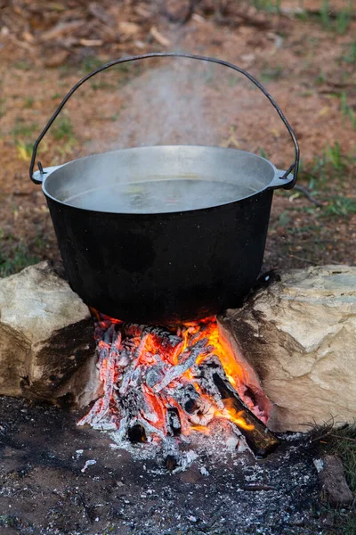 Açık ateşte hazırlanmış balık çorbası. Çaydanlıkta açık ateşte balık çorbası pişirmek. Turizm ve balıkçılıkta yemek pişirmek