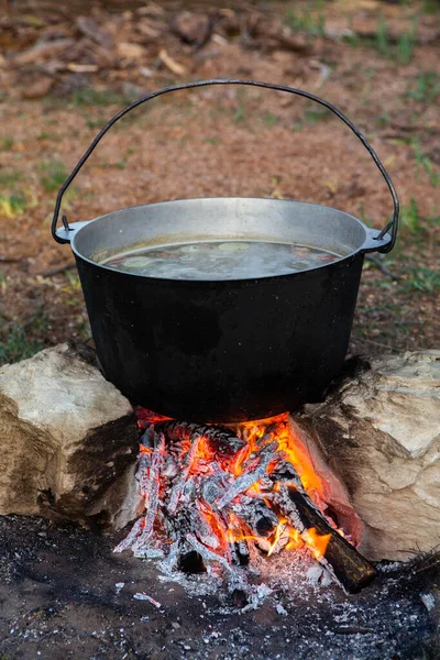 Açık ateşte hazırlanmış balık çorbası. Çaydanlıkta açık ateşte balık çorbası pişirmek. Turizm ve balıkçılıkta yemek pişirmek
