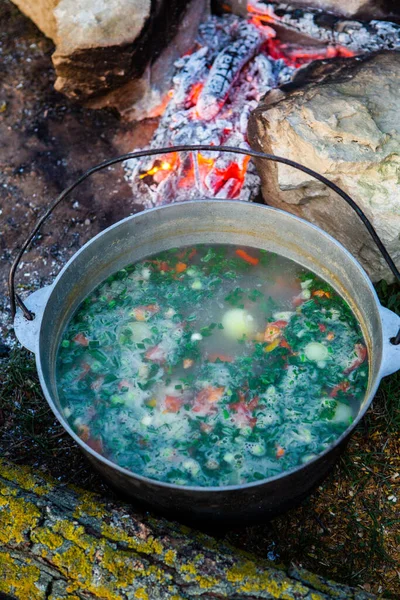Açık ateşte hazırlanmış balık çorbası. Çaydanlıkta açık ateşte balık çorbası pişirmek. Turizm ve balıkçılıkta yemek pişirmek