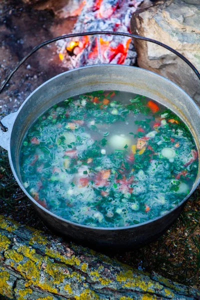 Açık ateşte hazırlanmış balık çorbası. Çaydanlıkta açık ateşte balık çorbası pişirmek. Turizm ve balıkçılıkta yemek pişirmek