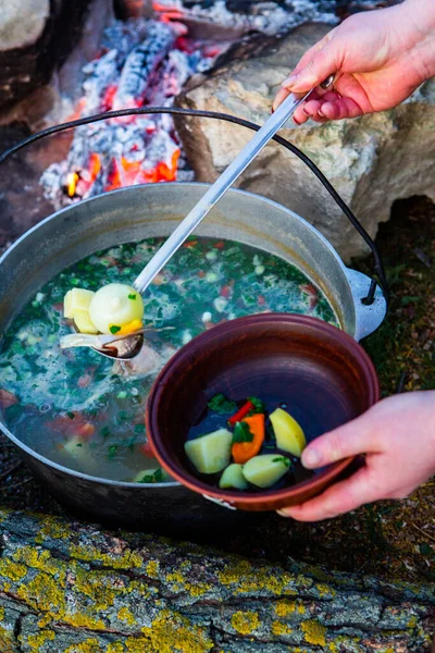 Açık ateşte hazırlanmış balık çorbası. Çaydanlıkta açık ateşte balık çorbası pişirmek. Turizm ve balıkçılıkta yemek pişirmek