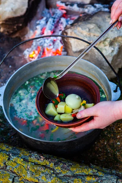 Açık ateşte hazırlanmış balık çorbası. Çaydanlıkta açık ateşte balık çorbası pişirmek. Turizm ve balıkçılıkta yemek pişirmek