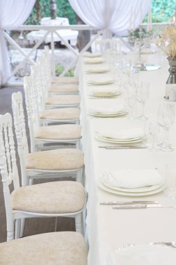 Empty banquet hall ready to receive guests on the summer terrace. white festive table