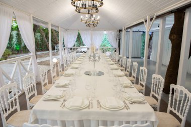 Empty banquet hall ready to receive guests on the summer terrace. white festive table