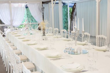 Empty banquet hall ready to receive guests on the summer terrace. white festive table