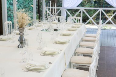 Empty banquet hall ready to receive guests on the summer terrace. white festive table