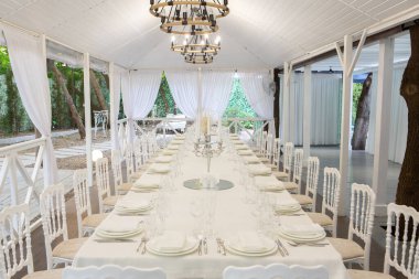 Empty banquet hall ready to receive guests on the summer terrace. white festive table