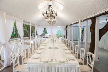 Empty banquet hall ready to receive guests on the summer terrace. white festive table