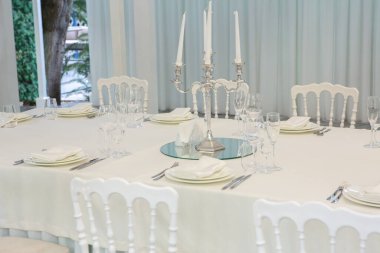 Empty banquet hall ready to receive guests on the summer terrace. white festive table