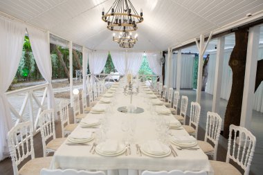 Empty banquet hall ready to receive guests on the summer terrace. white festive table
