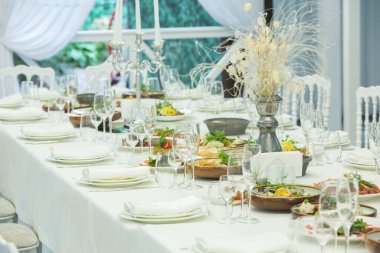 Empty banquet hall ready to receive guests on the summer terrace. white festive table