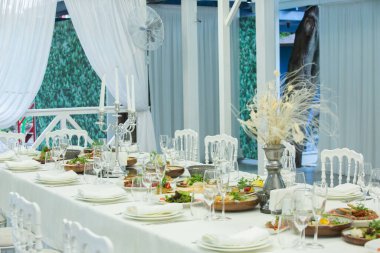 Empty banquet hall ready to receive guests on the summer terrace. white festive table