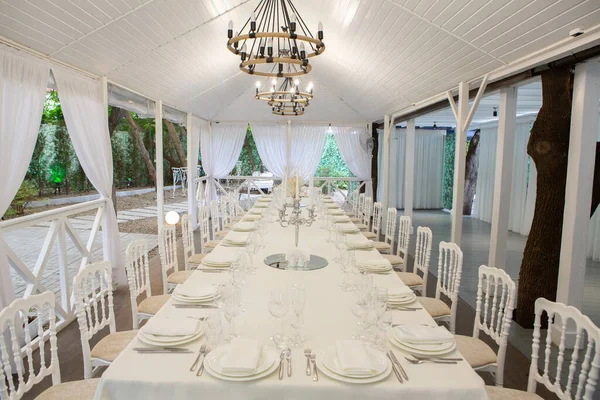 Empty banquet hall ready to receive guests on the summer terrace. white festive table