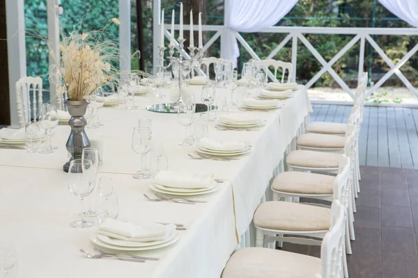 Empty banquet hall ready to receive guests on the summer terrace. white festive table