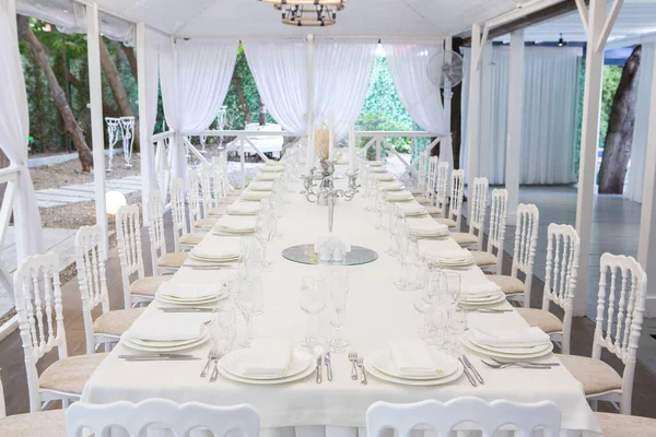Empty banquet hall ready to receive guests on the summer terrace. white festive table