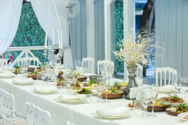 Empty banquet hall ready to receive guests on the summer terrace. white festive table