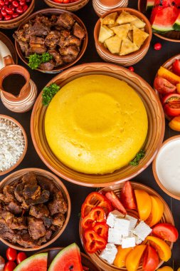 Homemade Romanian Food with polenta, meat, cheese and vegetables. Delicious corn porridge in clay dishes. Mamaliga or polenta, a traditional dish in Moldova, Hungary and Ukrainian cuisine.