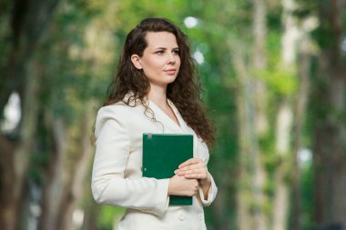 The portrait of a business woman with a notebook in her hand.  Smartly dressed girl outside. Successful white european woman