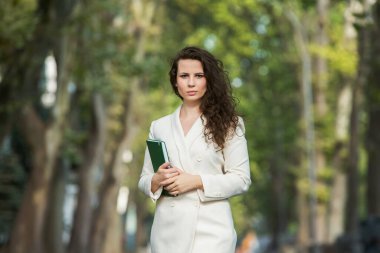 The portrait of a business woman with a notebook in her hand.  Smartly dressed girl outside. Successful white european woman