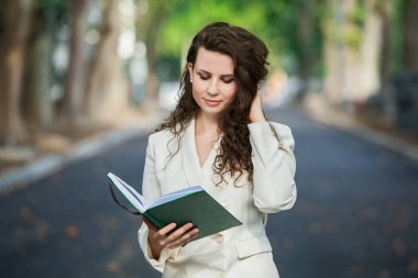 The portrait of a business woman with a notebook in her hand.  Smartly dressed girl outside. Successful white european woman