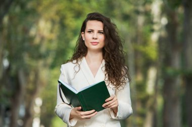 The portrait of a business woman with a notebook in her hand.  Smartly dressed girl outside. Successful white european woman