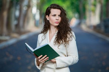 The portrait of a business woman with a notebook in her hand.  Smartly dressed girl outside. Successful white european woman