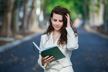 The portrait of a business woman with a notebook in her hand.  Smartly dressed girl outside. Successful white european woman