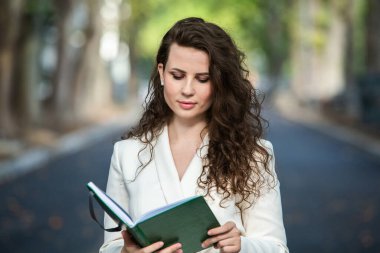 The portrait of a business woman with a notebook in her hand.  Smartly dressed girl outside. Successful white european woman