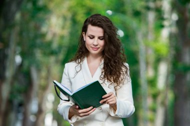 The portrait of a business woman with a notebook in her hand.  Smartly dressed girl outside. Successful white european woman