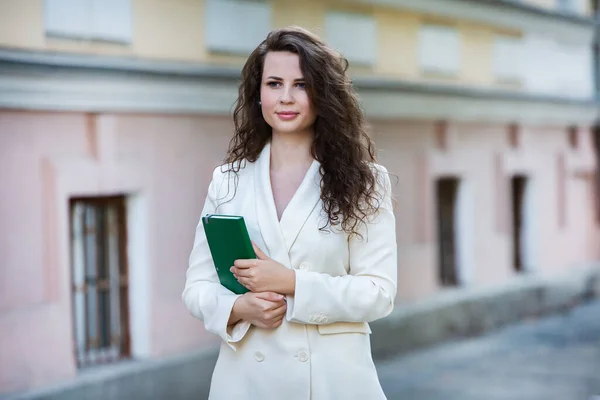 The portrait of a business woman with a notebook in her hand.  Smartly dressed girl outside. Successful white european woman