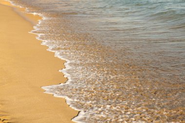 Girit adasının kıyısında altın kumu olan bir arka plan. Metin için kum ve berrak deniz suyuyla soyut yüzey.