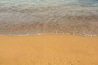 Girit adasının kıyısında altın kumu olan bir arka plan. Metin için kum ve berrak deniz suyuyla soyut yüzey.