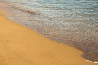 Girit adasının kıyısında altın kumu olan bir arka plan. Metin için kum ve berrak deniz suyuyla soyut yüzey.