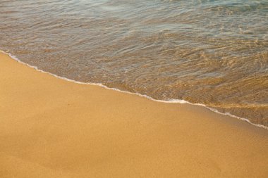 Girit adasının kıyısında altın kumu olan bir arka plan. Metin için kum ve berrak deniz suyuyla soyut yüzey.