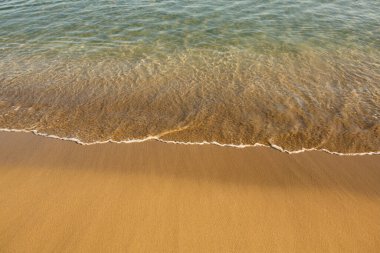 Girit adasının kıyısında altın kumu olan bir arka plan. Metin için kum ve berrak deniz suyuyla soyut yüzey.