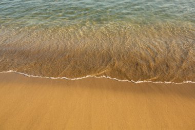 Girit adasının kıyısında altın kumu olan bir arka plan. Metin için kum ve berrak deniz suyuyla soyut yüzey.