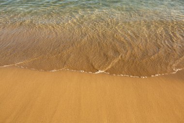 Girit adasının kıyısında altın kumu olan bir arka plan. Metin için kum ve berrak deniz suyuyla soyut yüzey.