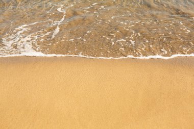 Girit adasının kıyısında altın kumu olan bir arka plan. Metin için kum ve berrak deniz suyuyla soyut yüzey.