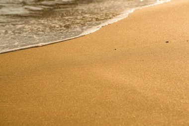 Girit adasının kıyısında altın kumu olan bir arka plan. Metin için kum ve berrak deniz suyuyla soyut yüzey.