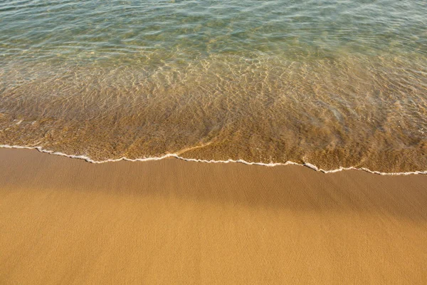 Girit adasının kıyısında altın kumu olan bir arka plan. Metin için kum ve berrak deniz suyuyla soyut yüzey.