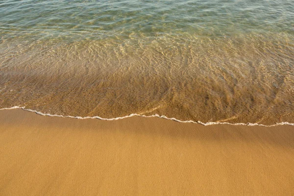 Girit adasının kıyısında altın kumu olan bir arka plan. Metin için kum ve berrak deniz suyuyla soyut yüzey.