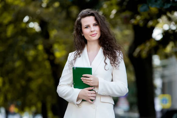 Portrait of a business woman with a notebook in her hand.  Smartly dressed girl outside. Successful white european woman