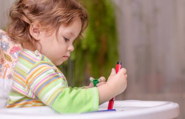 Çocukların yaratıcılığı kavramı. Elinde kalemler olan kirli bir bebek.