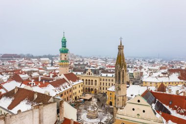 Sopron şehrinin göbeğindeki ikonik Ateş Kulesi ve Keçi Kilisesi 'ni gösteren hava manzarası. Karlı çatıları olan kış şehri..