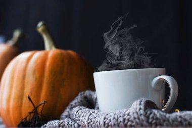 Sabah konsepti, kahvaltı, durgun hayat. Turuncu balkabağı, yapraklar ve örülmüş atkı ekoseli sonbahar kompozisyonu. Kahve, sıcak içecek, Şükran Günü, Cadılar Bayramı. Yan görünüm