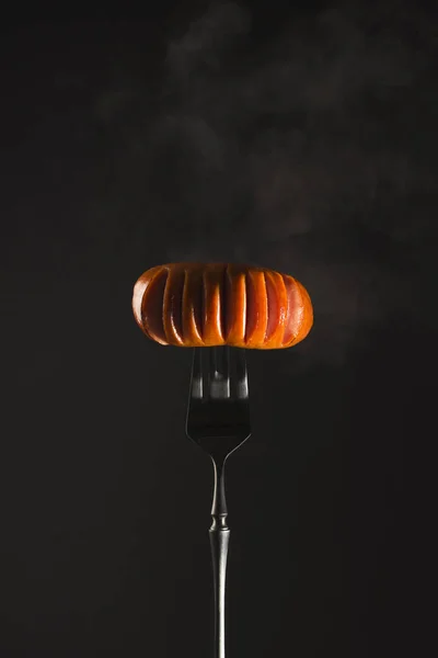 暗い背景に黒いフォークに煙と肉の熱いソーセージを焼きます コピースペース付き垂直画像 — ストック写真