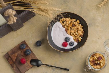 Masada bir kase ev yapımı müsli. Yoğurtlu granola ve hafif arkaplanda taze meyve suyu. Sağlıklı kahvaltı, doğal yemek ve diyet kavramı. Üst görünüm.