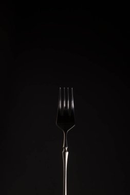 Siyah arka planda şık bir çelik çatal. Yakın plan. Tek renkli olsun. Dikey pozisyonda. Boşluğu kopyala