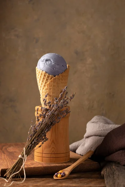 垂直位置 薰衣草在木制背景的华夫饼蛋筒里吃冰淇淋 乡村风格 普罗旺斯一束薰衣草花 免版税图库图片