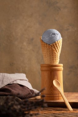Tahta arka planda waffle külahında doğal lavantalı dondurma. Köy tarzı. Provence. Bir buket lavanta çiçeği. dikey konum,